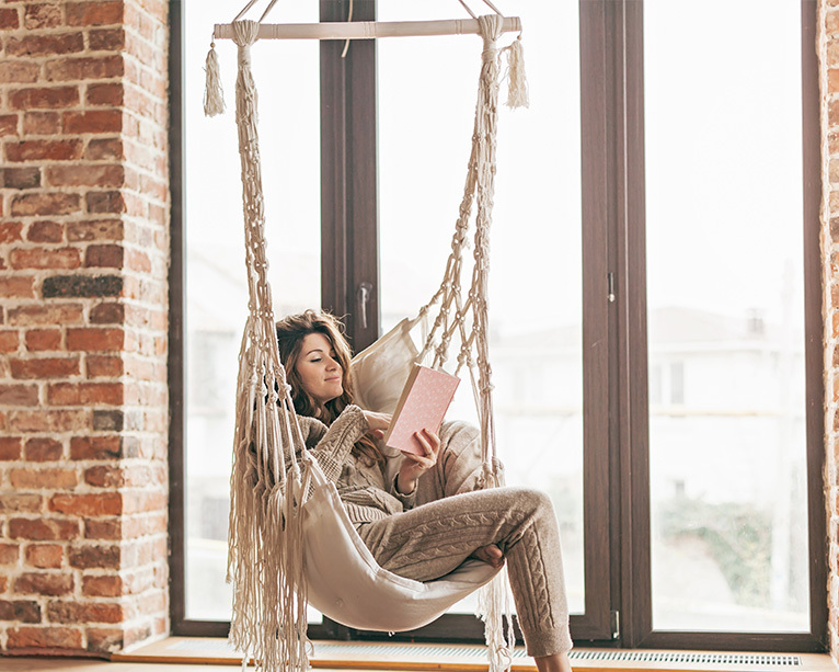 Girl reading in a hammock chair suspended from the ceiling