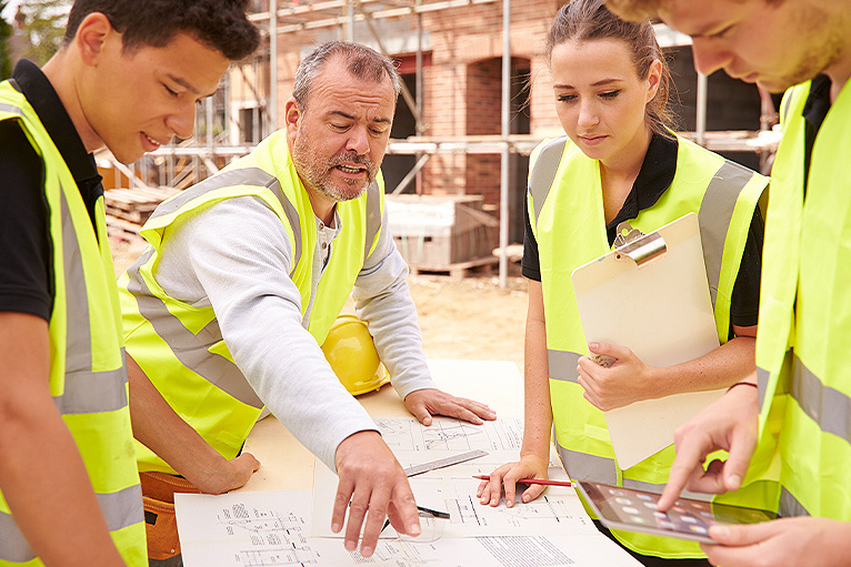 Builder and apprentices on site, looking at site plans