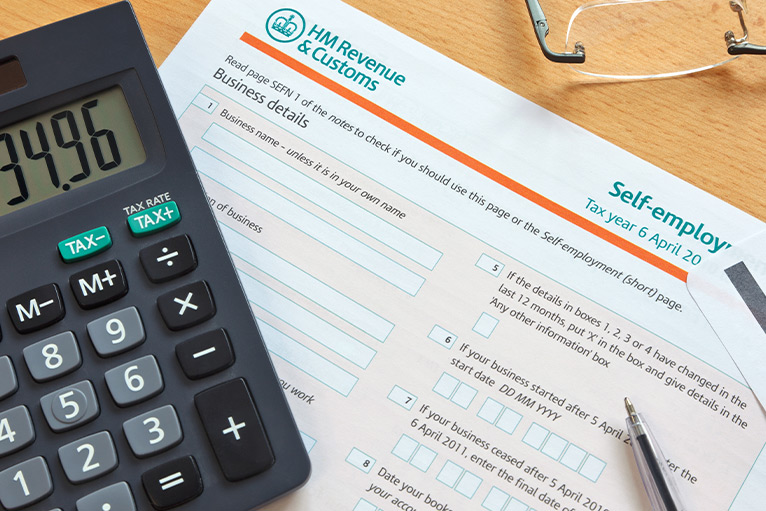 Self-assessment tax form, calculator and glasses on a table - coronavirus support