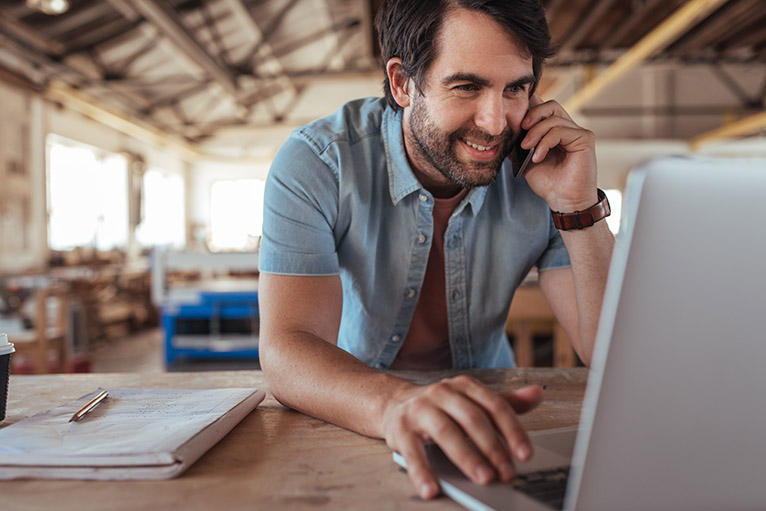 Trdaesman on phone and using laptop