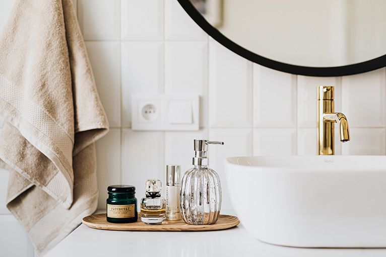 2021 home improvements: White bathroom sink and gold tap next to skincare products