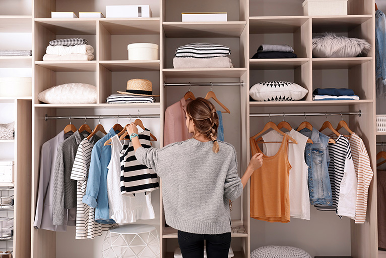 Person choosing clothing from wall mounted wardrobe