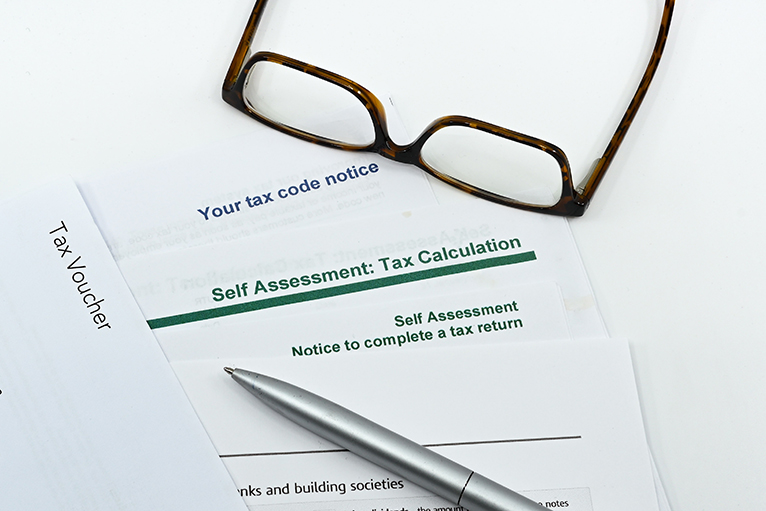 Tax documents, pen and glasses on table