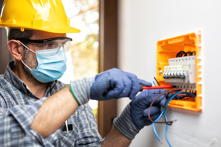 Electrician wearing mask whilst working inside home.