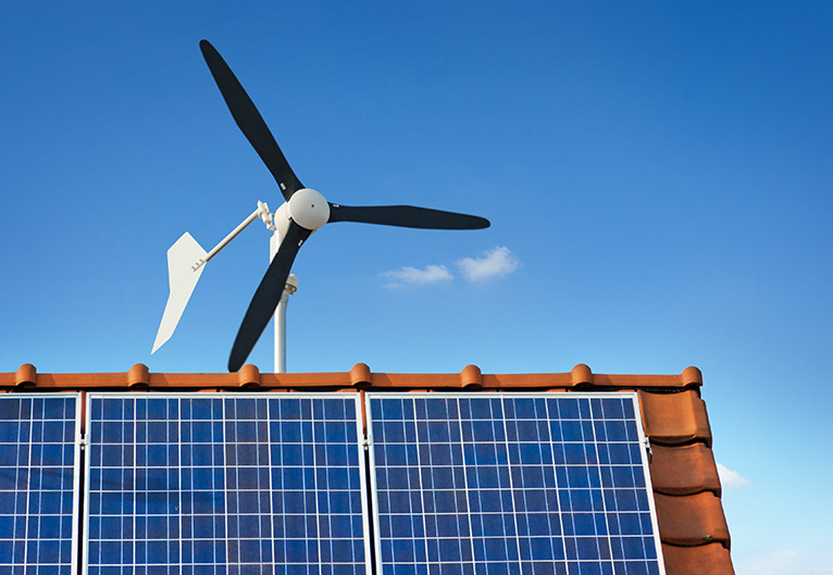 Small wind turbine behind house with solar panels