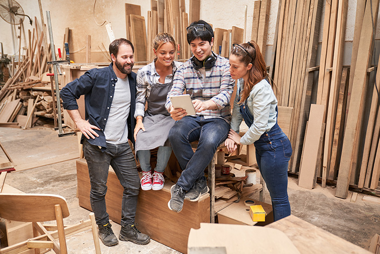 Group of carpenters in workshop looking at tablet