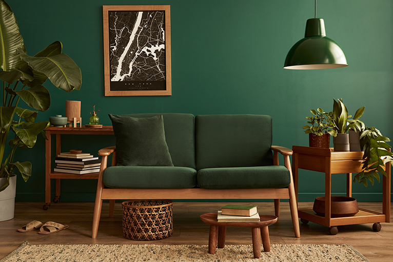Lounge decorated in green and brown, with plants placed on either side of a sofa.