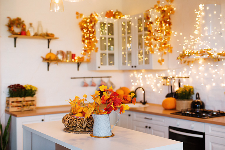 Autumnal themed kitchen interior. Decorated with red and orange leaves and fairy lights. 