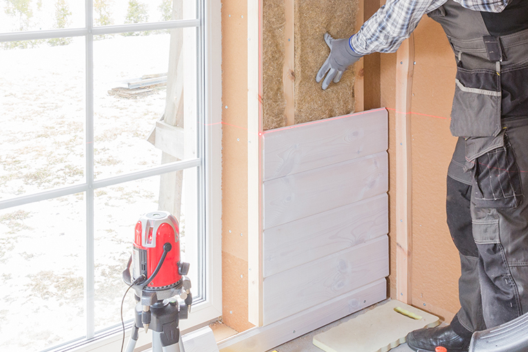 Construction worker thermally insulating room with wood fiber plates and heat-isolating natural hemp material.