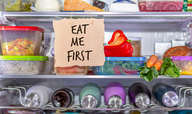 Inside of a fridge with labeled containers storing leftover food. 