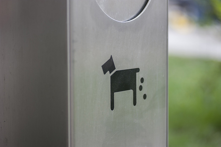 Metal dog-waste bin with black image of a dog pooping. 