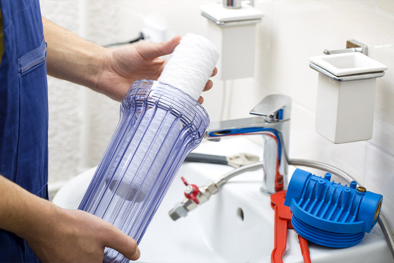 Bathroom fitter installing water filtering system