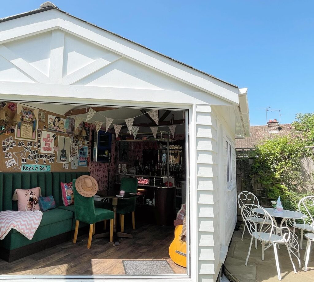 a home bar in a garden shed with a green sofa and lots of decorations on the wall