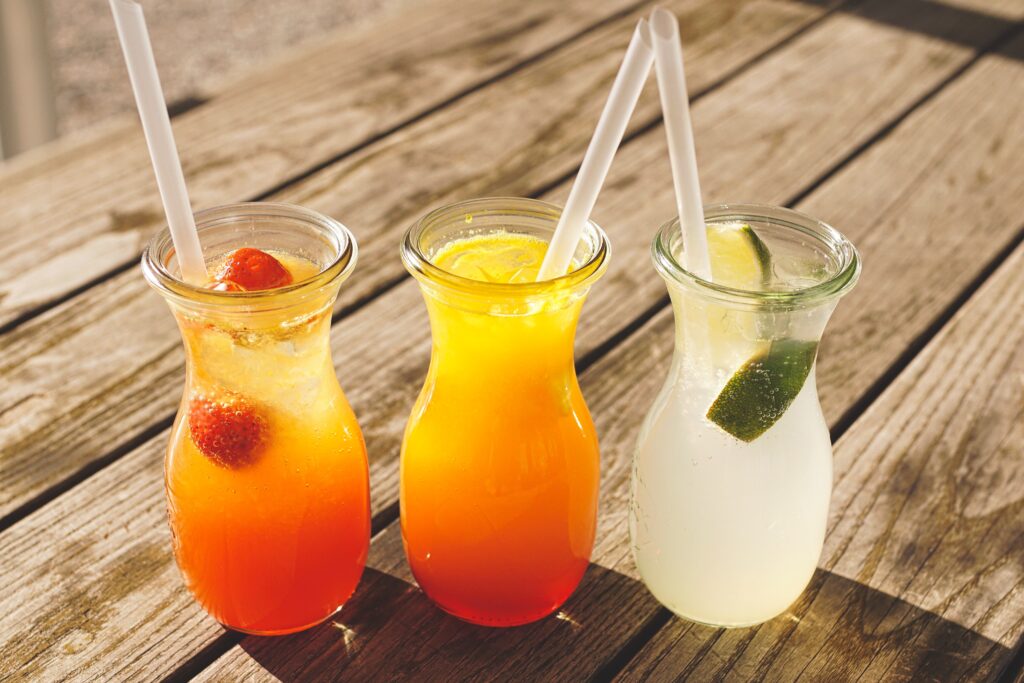 three full cocktails glasses sitting on a wooden bar