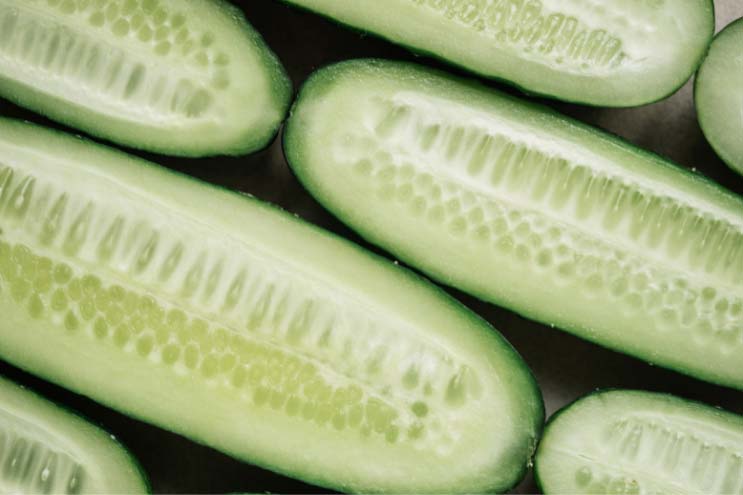 a photo of a cucumber halved lengthways with the insides of the slices facing upwards so seeds are on show