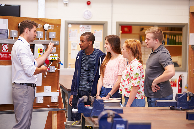 4 students being spoken to by a teacher