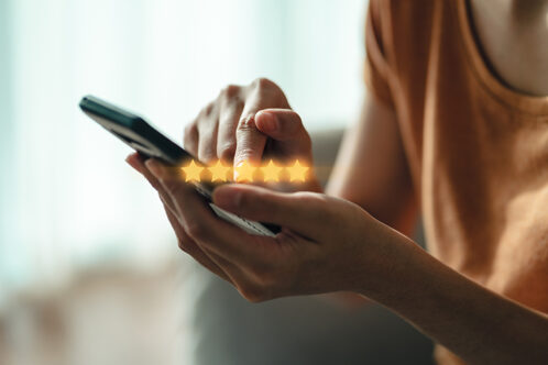 Picture of a close up of hands holding a phone with five stars illustrated to show rating