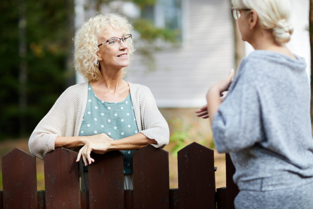 Beeld van twee vrouwen die over een hek praten