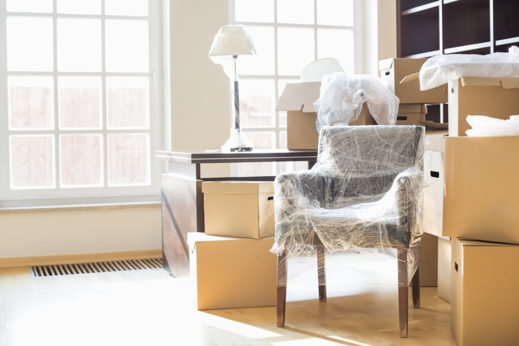 Picture of a room with moving boxes and a chair wrapped in bubble wrap