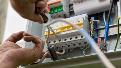 Picture of an electrician fastening a fuse board circuit breaker onto a consumer unit electrical panel